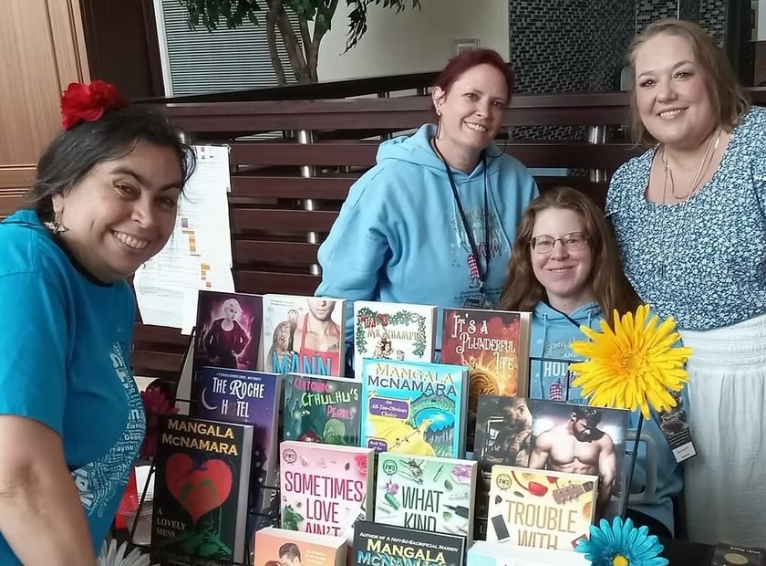 KRW members behind a table of their books at a signing event
